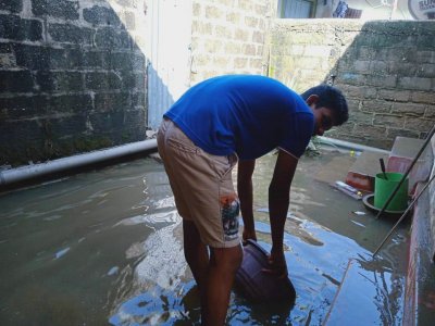 SriLanka_Ditwah_007_web Mann steht im Innenhof seines Hauses und schippt Wasser.