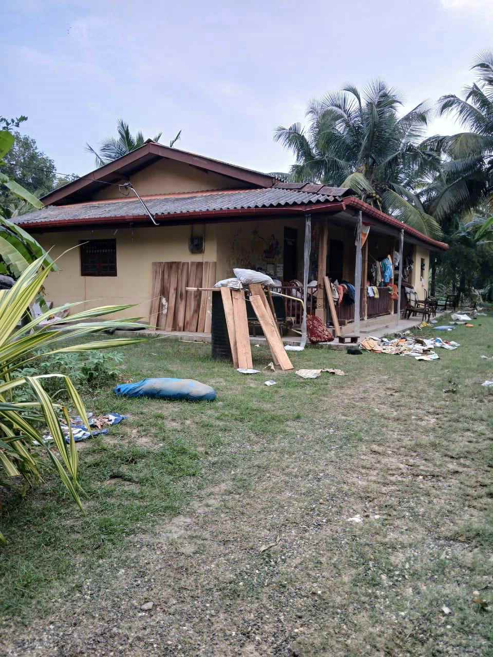 SriLanka_Ditwah_010_web Vor einem Haus in Sri Lanka sind Kleidung und Holzbretter zum Trocknen verteilt.