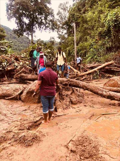 SriLanka_Ditwah_014_web Menschen stehen im Schlamm und versuchen umgestürzte Bäume zu umgehen.